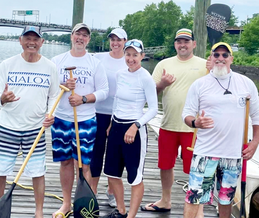 Photo of people standing on a dock with canoe paddles