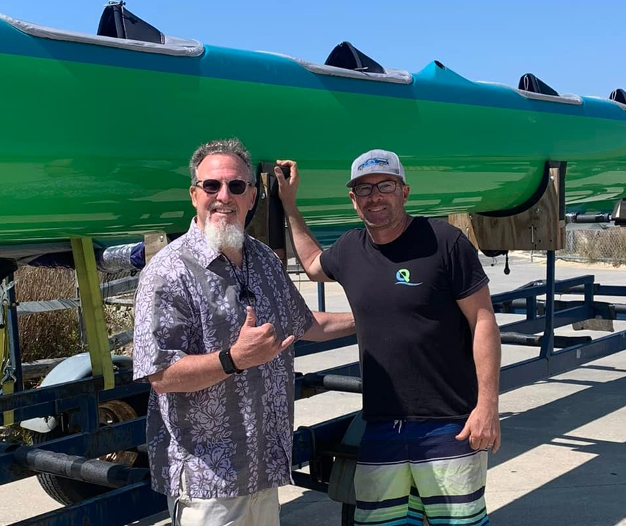 Photo of two men standing next to a canoe