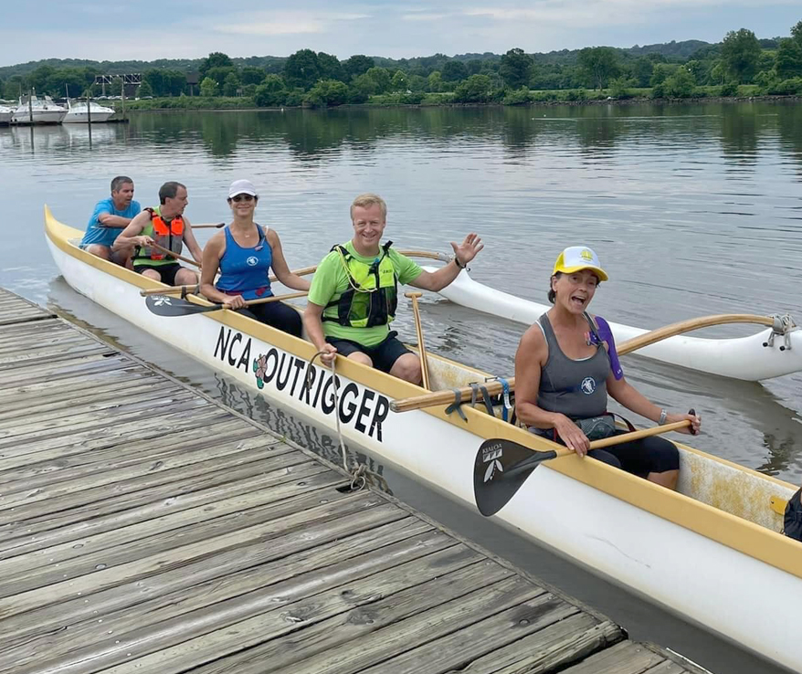 Photo of people sitting in a canoe next to a dock