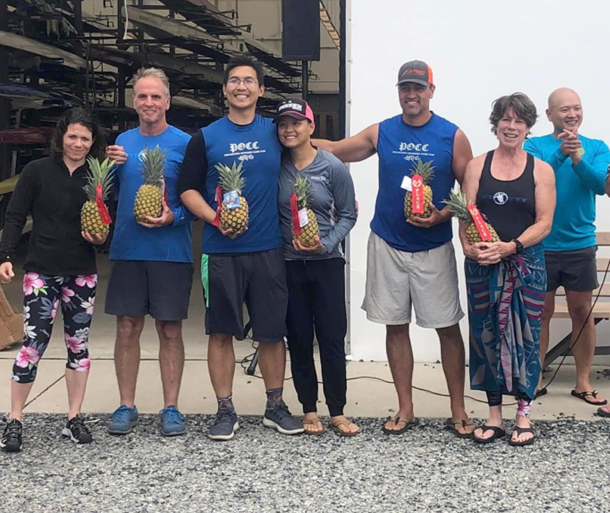 Photo of people smiling and holding pineapples